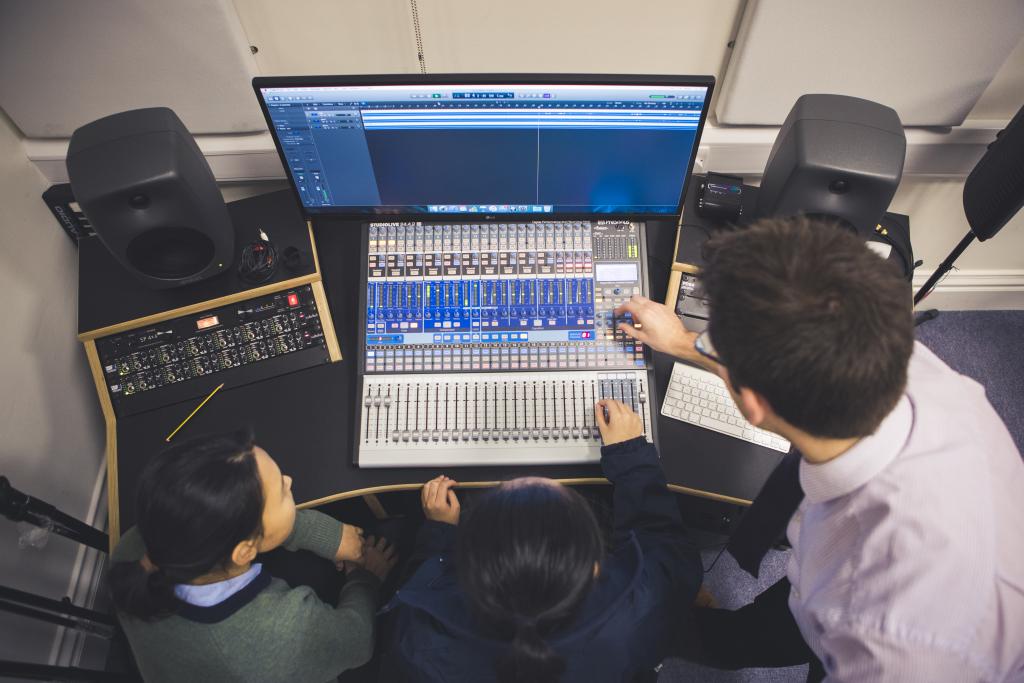 Viewed from above, a teacher and two students sit working with equipment in the new recording studio at Cheltenham Ladies' College
