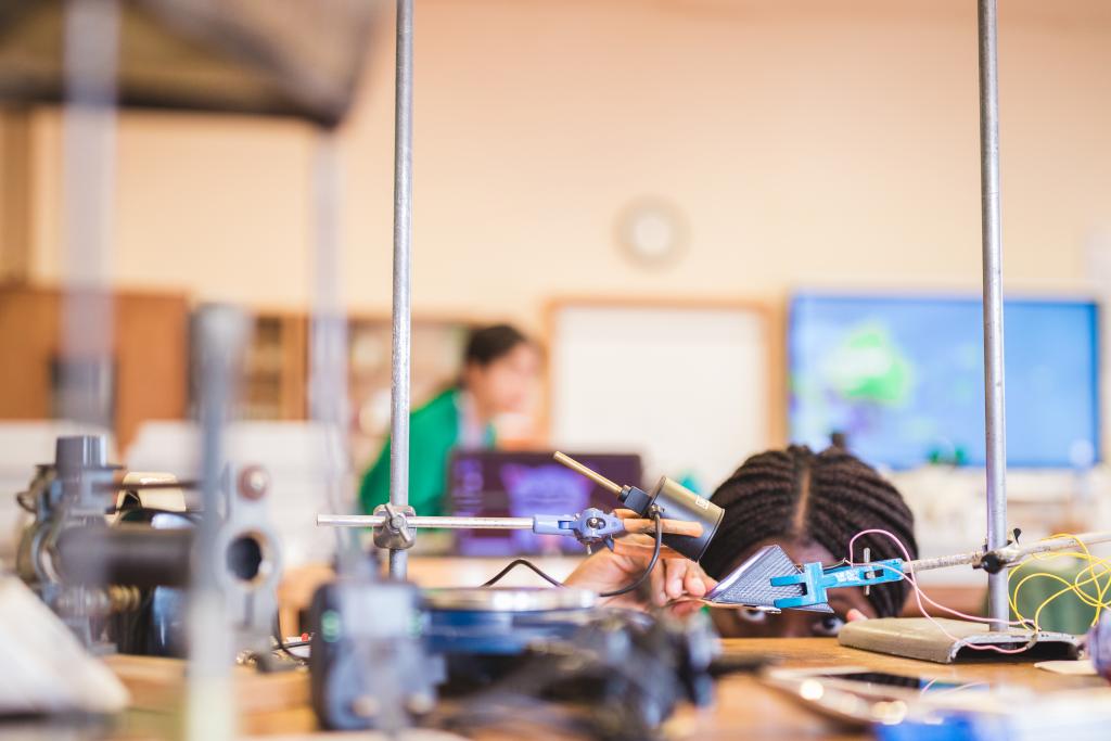 A CLC sixth form student bends down to get a good view of her experiment during her chemistry lesson